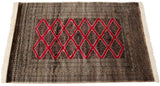 Vintage Pakistani rug from an angle, showing the full, dense pile and red diamond medallions.
