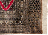 Corner detail of a Pakistani Turkmen rug's intricate geometric borders and original ivory fringe.