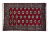 Vintage Pakistani Turkmen design rug with repeating diamond-shaped gul medallions in cherry red, black, and ivory.
