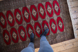 A person's perspective of the repeating gul medallions and cherry red pile on a vintage Pakistani Turkmen rug.