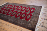 Angled view of a vintage Pakistani Turkmen rug showing its repeating red diamond guls.