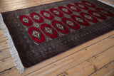 Lengthwise view of a vintage Turkmen rug with a plush red pile and intricate geometric borders.
