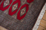 Corner view of the vintage Turkmen rug's intricate geometric border and clean ivory fringe.