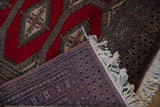 Folded corner of the Turkmen rug reveals its hand-knotted back weave and original ivory fringe.