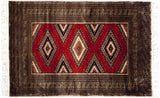 Hand-knotted rug corner, geometric borders in cherry red, black, and beige.