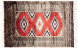 Vintage Turkmen rug: intricate geometric borders in beige and black, cherry red stepped diamond motifs, and fringe.