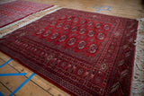 Angled view of a vintage Bokhara rug showing its lustrous cherry red pile and geometric guls.