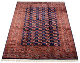 Angled view of a vintage Bokhara carpet emphasizing the lustrous navy pile and repeating gul medallions.