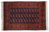 Fine vintage Bokhara rug with allover rust and ivory gul medallions on a deep navy blue field.