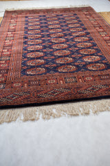 Angled view of a vintage Bokhara rug highlighting its plush navy wool pile and clean ivory fringe.
