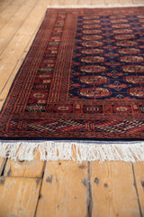 Low angle view of a plush Bokhara rug, detailing its clean white fringe and rust geometric border.