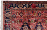 Vintage Pakistani Caucasian rug corner: navy geometric border, dusty raspberry field, white fringe.