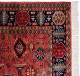 Pakistani Caucasian design rug corner, showing dusty raspberry field, navy geometric border, and fringe.