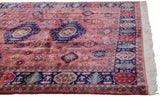 Corner of a vintage Pakistani Caucasian design carpet with navy geometric border and light fringe.