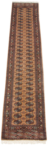 Geometric floral gul medallions in camel, navy, and pale terra cotta on the Bokhara runner.
