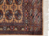 Vintage Bokhara runner: camel field with detailed gul medallions, geometric navy border, ivory fringe.