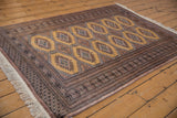 Side perspective of a vintage Pakistani Turkmen design rug highlighting intricate borders and ochre field.