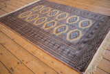 Angled view of a vintage Pakistani rug showing its repeating gul medallions and multi-layered geometric borders.
