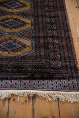 Secured end of a Turkmen rug showing the intact ivory fringe and intricate geometric border.