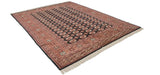 Detailed geometric terra cotta and chestnut borders with ivory fringe on a vintage Bokhara rug.