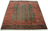 Fine Bokhara square carpet angled to display its lustrous emerald and rust geometric pattern.