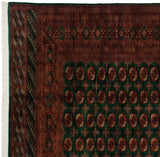 Corner of a vintage Bokhara rug with detailed rust borders, emerald field, and intact white fringe.