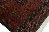 Corner detail of a vintage Bokhara carpet with plush wool pile, emerald green border, and ivory fringe.