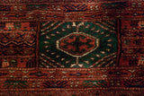 Detail of a tight-weave gul medallion with emerald green, rust, and navy on a vintage Bokhara carpet.