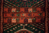 Macro detail of the hand-knotted gul medallions in rust, emerald green, and navy blue wool.