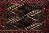 Close-up of a Bokhara carpet's geometric gul medallion in emerald green, rust, and navy blue.