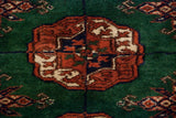 A detailed gul medallion in rust, navy, and ivory on a plush emerald green wool pile.