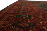 Angled perspective showing the linear columns of a fine vintage Bokhara carpet in rust and green.