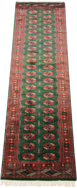 A view down the length of a fine Bokhara runner showing its lustrous emerald green pile and gul medallions.