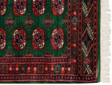 Corner detail of a fine Bokhara rug showing its intricate border and clean ivory fringe.