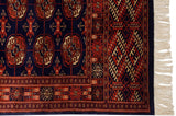 Navy blue and rust Bokhara rug border featuring geometric patterns, gul design, and ivory fringe.