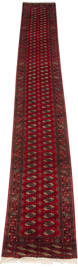 Angled view of a vintage Bokhara runner with columns of gul medallions on a cherry red field.
