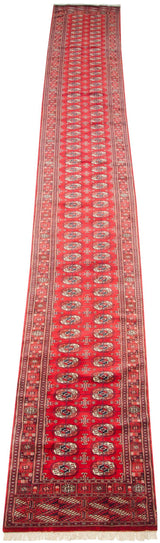 High-angle view of a long vintage Bokhara runner, emphasizing the repeating gul pattern on its cherry red field.