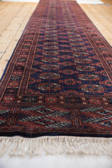 Vintage Bokhara runner viewed from a low angle, showing the repeating gul medallions.