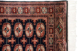 Corner of Bokhara rug, black field with terra cotta geometric borders, intact selvage, white fringe.