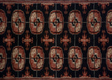 Upper border and repeating Bokhara gul medallions in black, terra cotta, and ivory tones.
