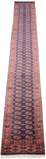 Angled perspective of a vintage Bokhara runner with repeating gul medallions and rust borders.