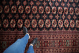 Detailed view of a vintage Bokhara carpet's plush texture and repeating elephant's foot design.