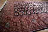 Intricate geometric borders in terra cotta and black on the corner of a fine Bokhara carpet.