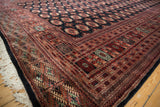 Intricate geometric borders in terra cotta, black, and ivory on a plush vintage Bokhara carpet.
