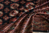 Intricate geometric border and gul medallions on the plush, silk-like pile of a Bokhara carpet.