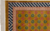 Art Deco rug corner with ochre field, blush and green floral motifs, blue cube border.