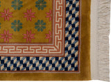 Corner of Art Deco rug with ochre floral field and illusion 3D cube border.