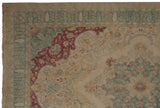 Corner spandrel detail with dusty raspberry red and seafoam green on a vintage distressed Kerman design carpet.