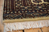 Intact cream fringe and faded lime green selvage of the vintage Indian Bokhara rug.