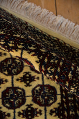 Vintage Indian Bokhara rug, rolled view, displaying geometric guls, dark red, navy, cream, fringe.